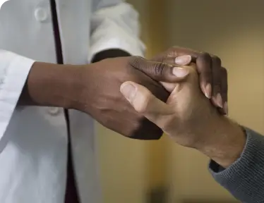 A doctor and a patient shake hands, symbolizing trust and collaboration in a healthcare setting.